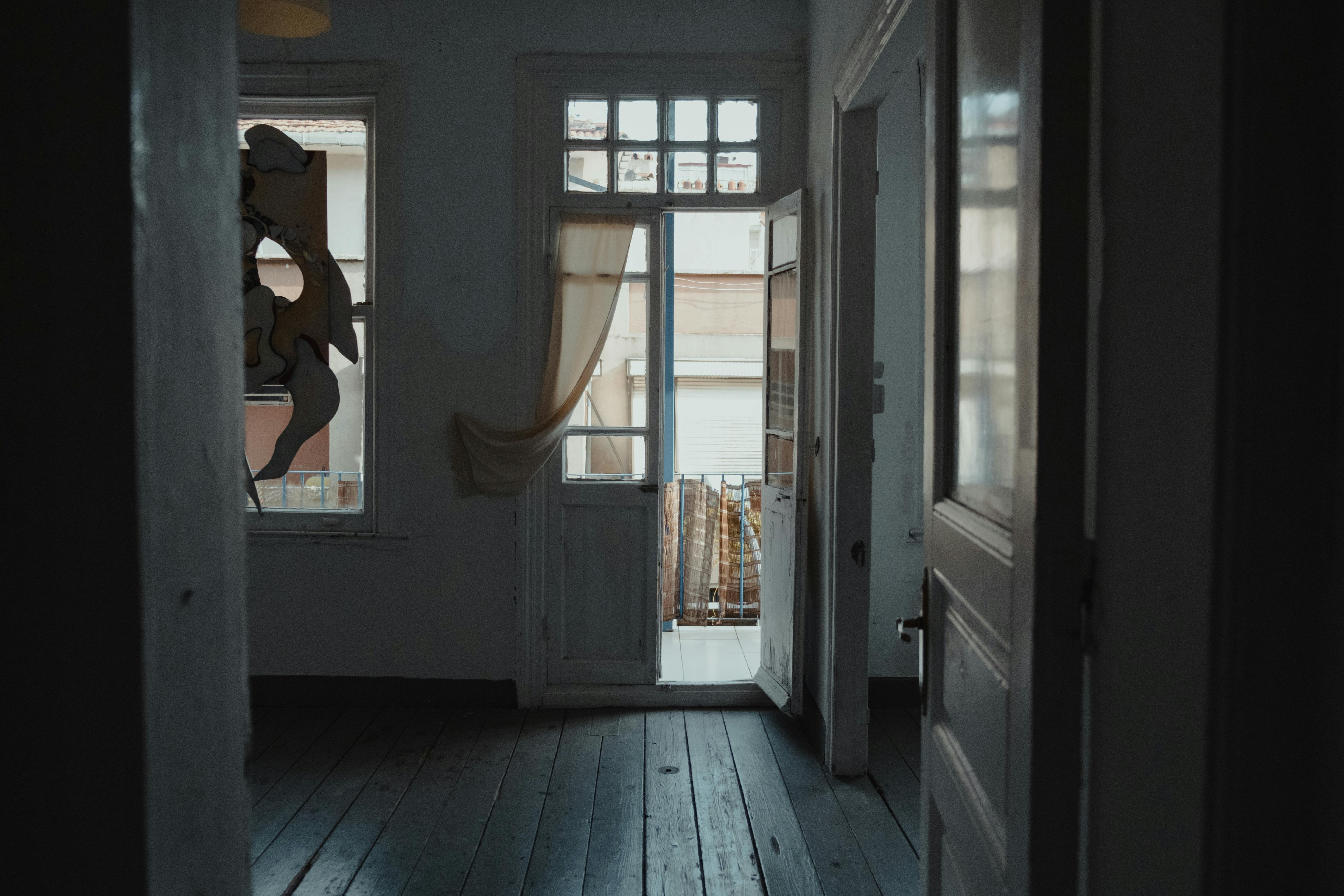 A dim interior hallway with daylight coming through an open door.